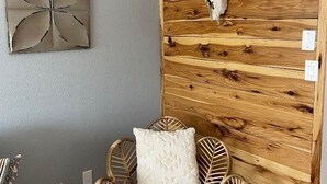 A room with a wooden wall panel, a white cushioned chair, and a wall-mounted skull decoration. - Comfy, contemporary, quiet retreat with views of the Petroglyphs  (Albuquerque)
