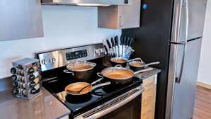 Une cuisine moderne équipée d’appareils électroménagers en acier inoxydable, notamment une cuisinière avec des casseroles, un réfrigérateur et un bloc à couteaux.