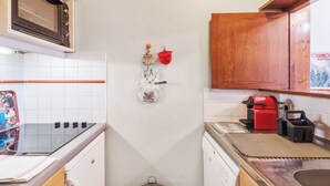 A compact kitchen with a microwave, stove, and espresso machine. - Appartement Courmayeur - Welkeys (Chamonix-Mont-Blanc)
