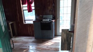 A wooden interior with a herringbone floor pattern, a green door, and a window with red curtains. - Primitive Cabin in the woods. A place to unplug, unwind, and relax! (Parthenon)