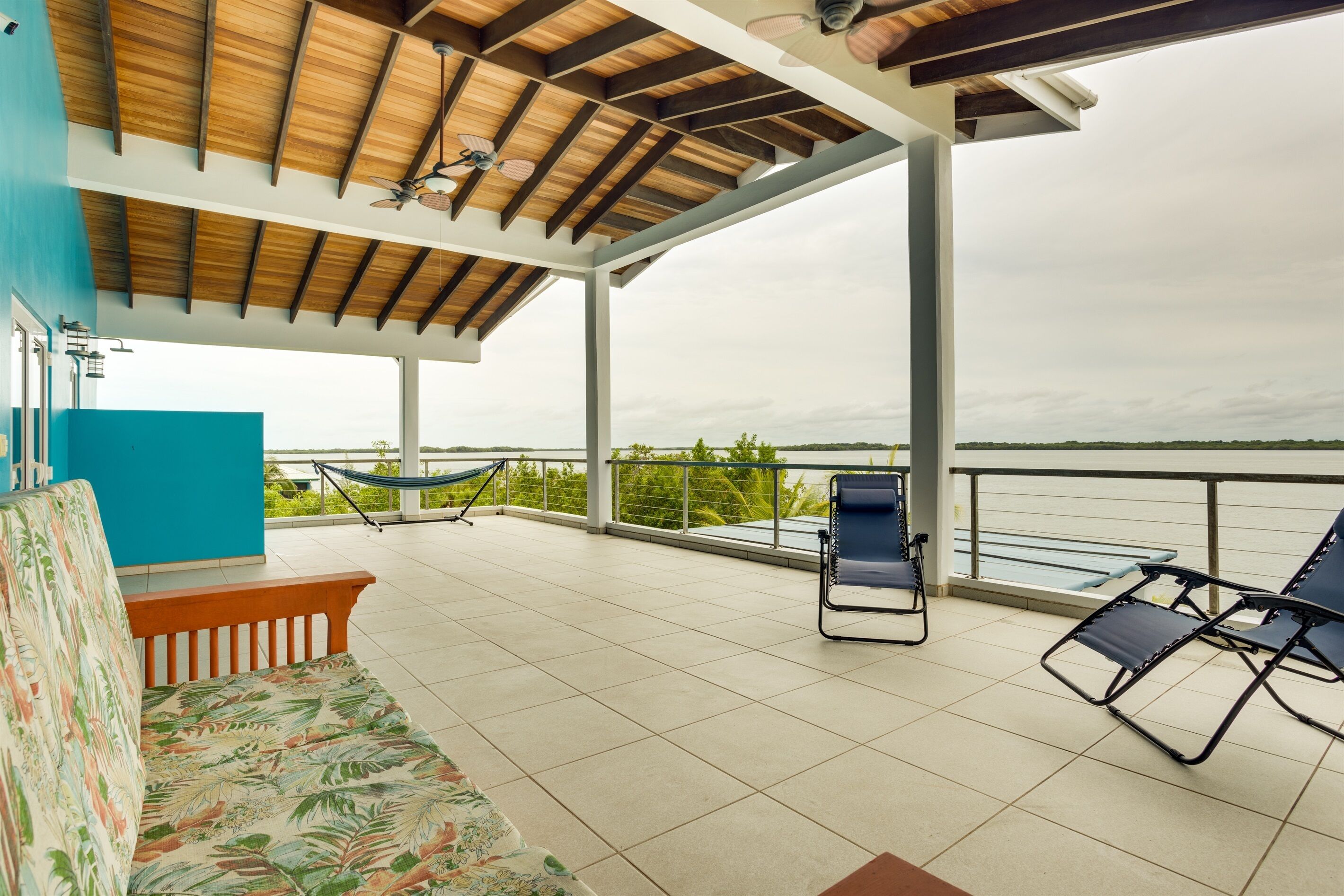 A covered outdoor seating area with a hammock, lounge chairs, and a sofa.