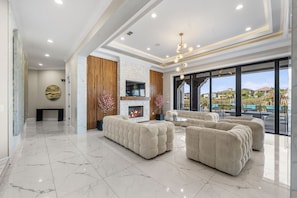 A spacious living area with a fireplace, plush seating, and a large window offering a view of the outdoors.
