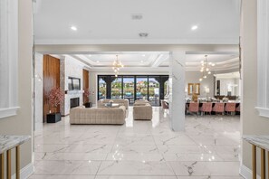 Uma sala de estar ampla com lareira, assentos confortáveis e vista para uma piscina.