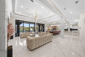 A spacious living area with a large sectional sofa, a dining table, and a kitchen in the background.