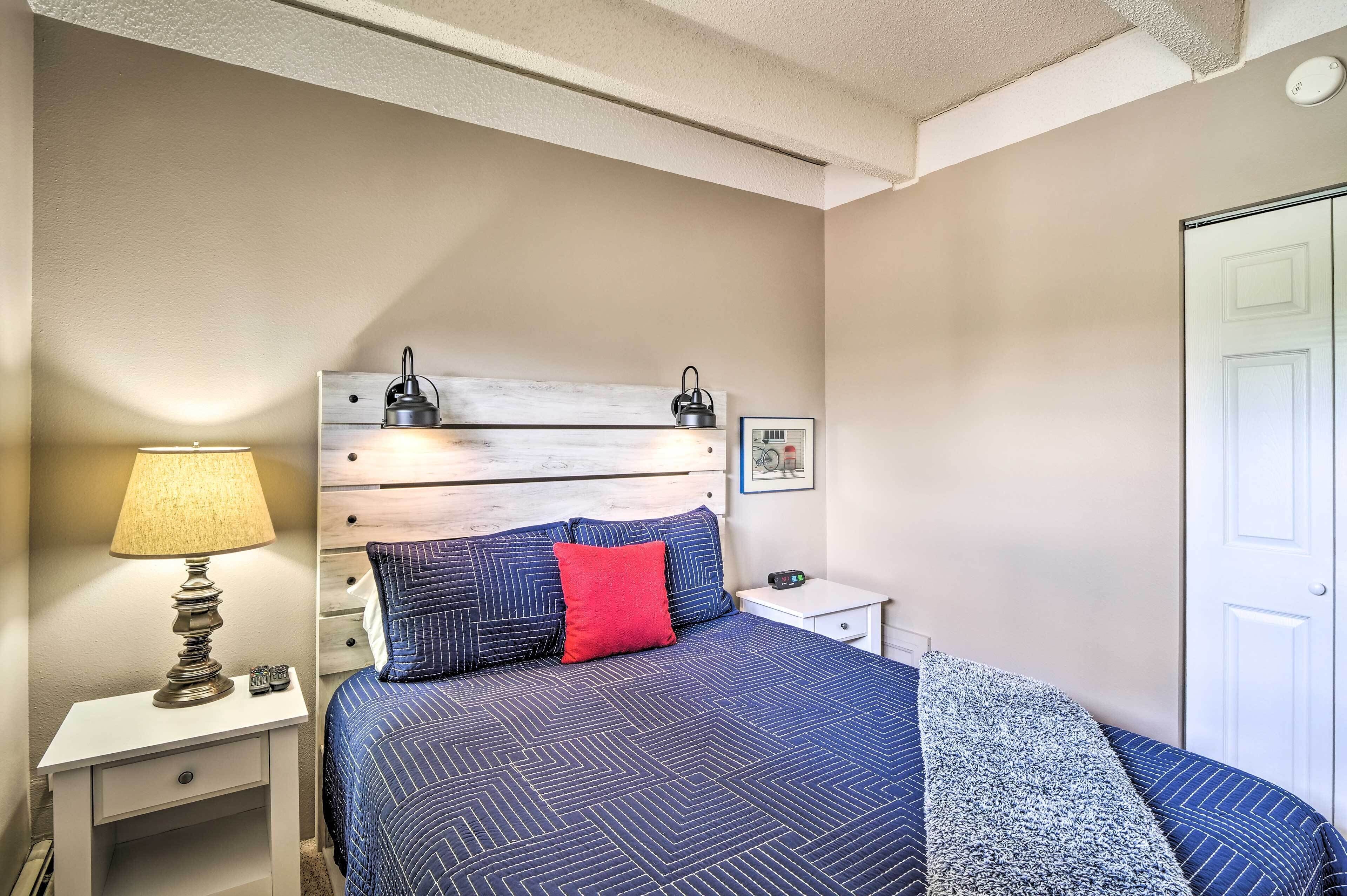 Une chambre à coucher avec un lit, une table de chevet, une lampe et une porte.