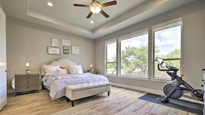 A bedroom with a bed, a desk, a standing fan, and a stationary bike. - Upscale Austin Area Escape: Families Welcome! (Austin)