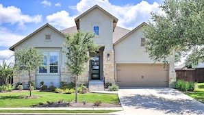 A two-story house with a garage, a front porch, and a well-maintained lawn. - Upscale Austin Area Escape: Families Welcome! (Austin)