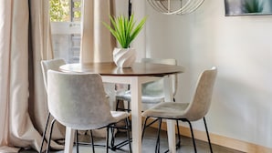 A dining area with a round table, four chairs, a potted plant, and a wall-mounted plant shelf. - Beacon Hill 1BR - Rooftop + Patio - Near VA Medical - Monthly Stays (Seattle)