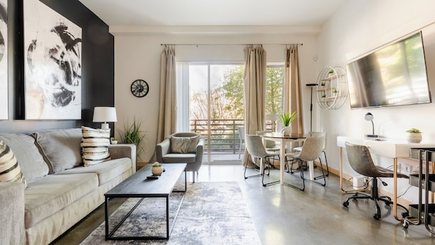 A modern living room with a sofa, coffee table, and dining area. - Beacon Hill 1BR - Rooftop + Patio - Near VA Medical - Monthly Stays (Seattle)