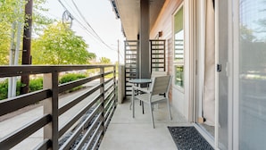 A balcony with a metal railing, a table with chairs, and a sliding glass door. - Beacon Hill 1BR - Rooftop + Patio - Near VA Medical - Monthly Stays (Seattle)