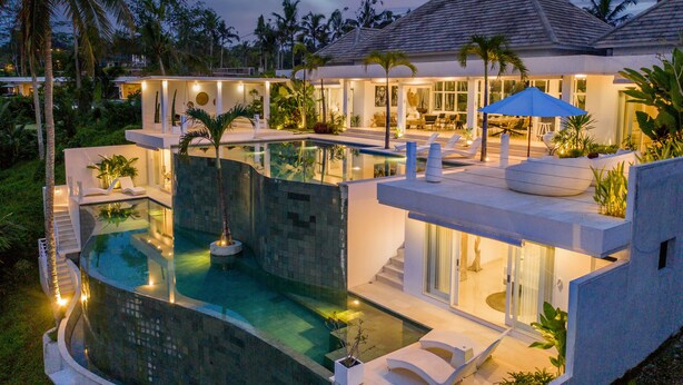 Une maison moderne dotée d’une piscine, d’un espace salon extérieur et d’une terrasse bien éclairée.