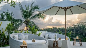 Un salon sur le toit, avec des canapés en osier, des bougies et un grand parasol.
