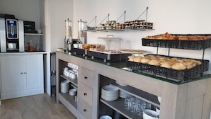 Een buffetopstelling met diverse gerechten, een koffieapparaat en een waterdispenser.