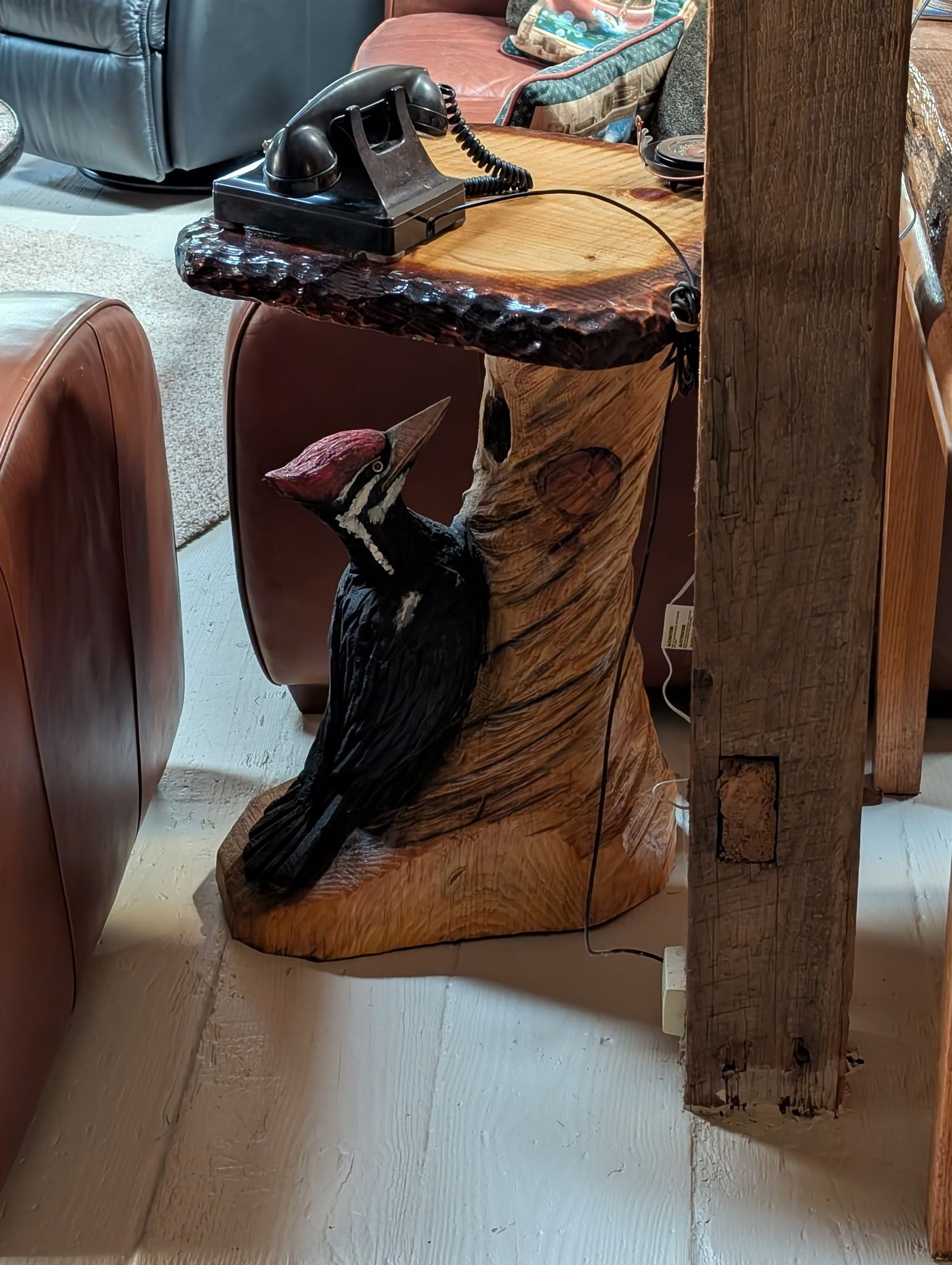 Una mesa de madera con un diseño de pájaro tallado y un teléfono encima.