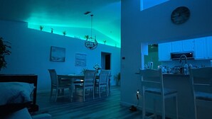 Ein modernes Wohnzimmer mit Essbereich, Küche und einer Treppe, die in eine obere Ebene führt.