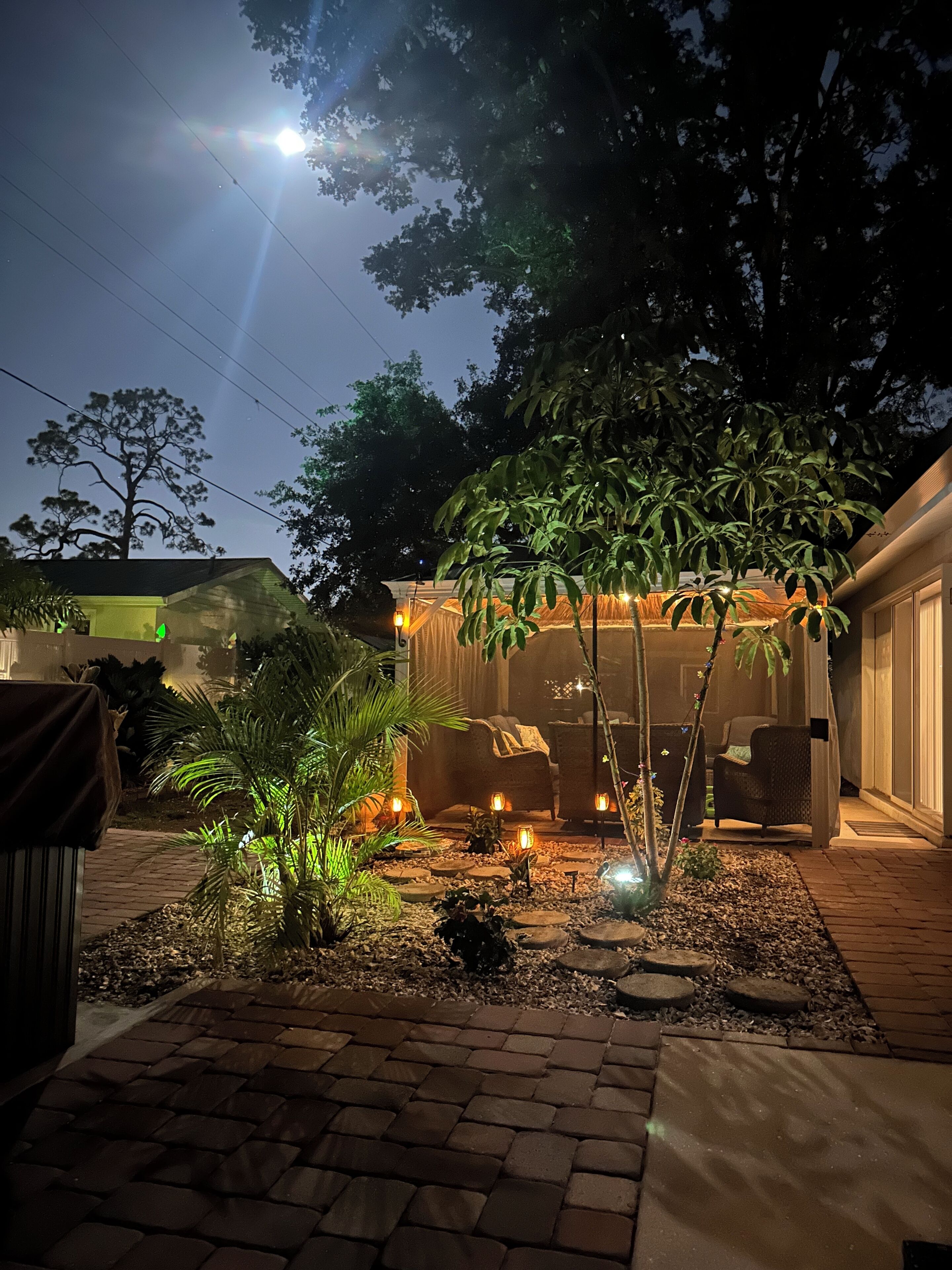A patio area with a pergola, outdoor furniture, and decorative lighting.