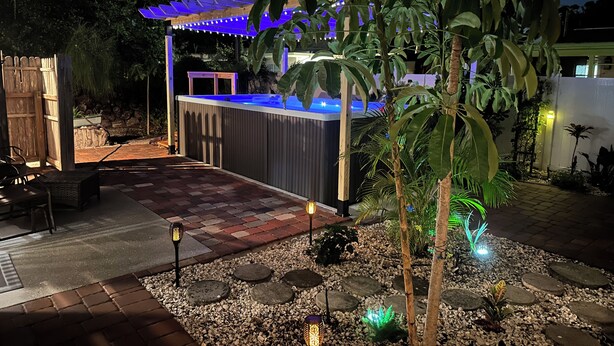 Ein Patio mit Whirlpool, Sitzgelegenheiten und dekorativer Beleuchtung.