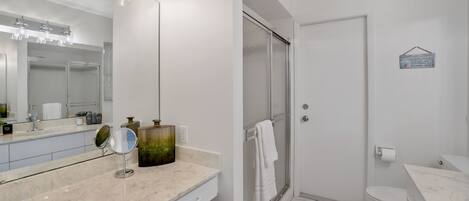 A modern bathroom with a marble vanity, a glass shower enclosure, and a white toilet.