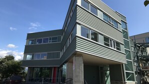A multi-story building with a modern architectural design, featuring large windows and a flat roof. - Stylish Downtown Loft 201-Alaska Railroad Suite (Anchorage)