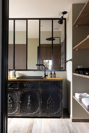 A bathroom with a wooden vanity, a large mirror, and a shelf with towels. - Les Chambres de Casarina (Bonifacio)