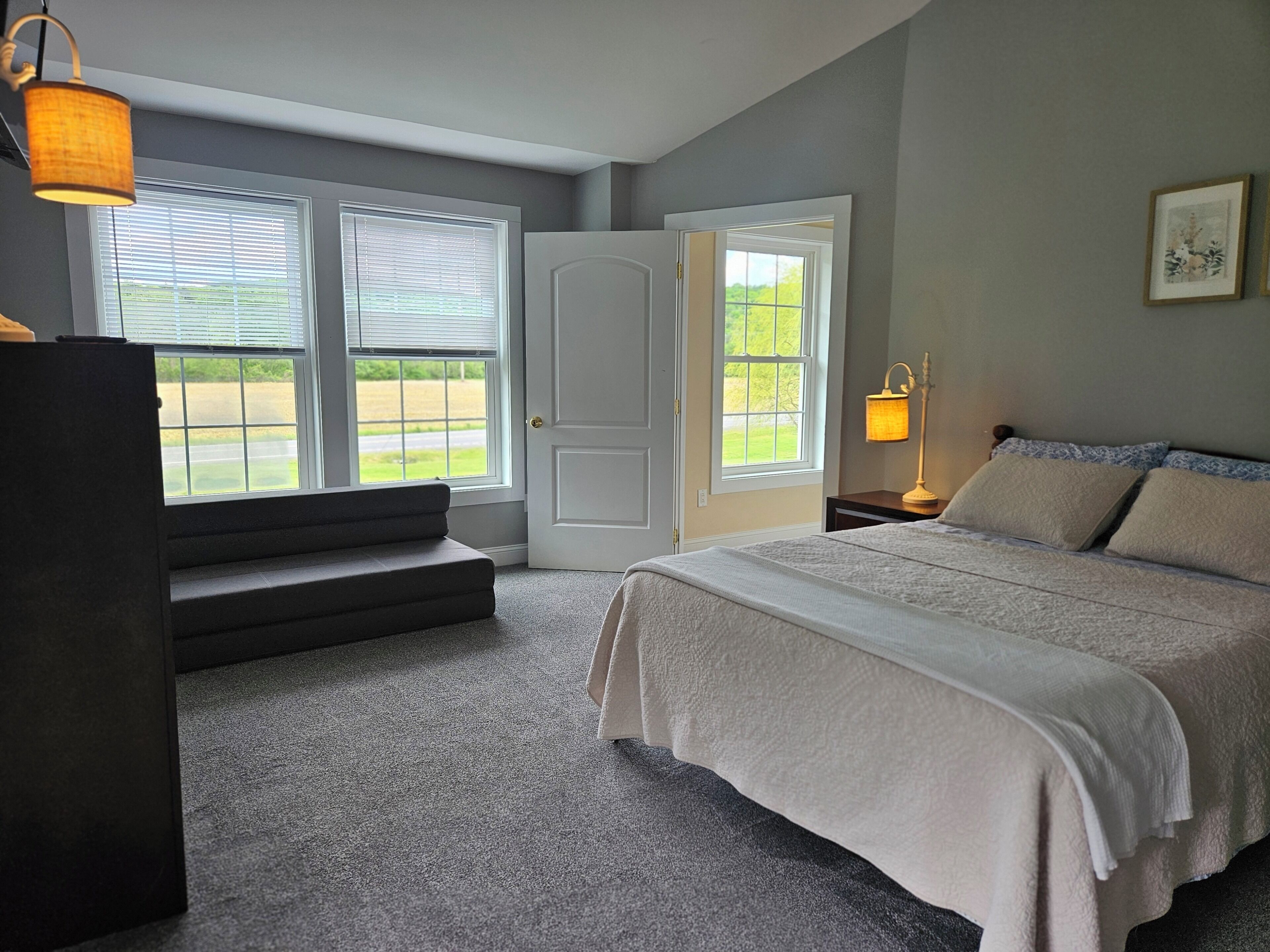 Une chambre à coucher avec un lit, une table de chevet, une lampe, une fenêtre et une porte.