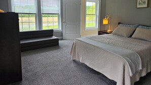 A bedroom with a bed, a nightstand, a lamp, a window, and a door.