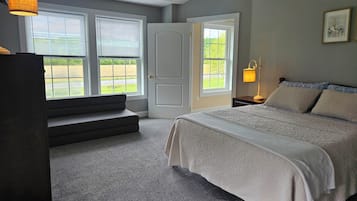Une chambre à coucher avec un lit, une table de chevet, une lampe, une fenêtre et une porte.