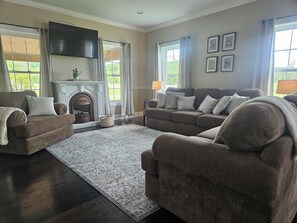 A living room with a fireplace, sofas, a rug, and a TV.