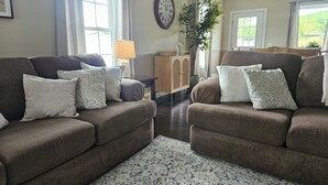 A living room with two sofas, a clock, a lamp, and a plant.