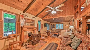 A cozy cabin interior with a wooden ceiling, a fireplace, a sofa, and a dining area. - Beautiful Jay Peak Home Near Creek & Waterfalls! (Jay)