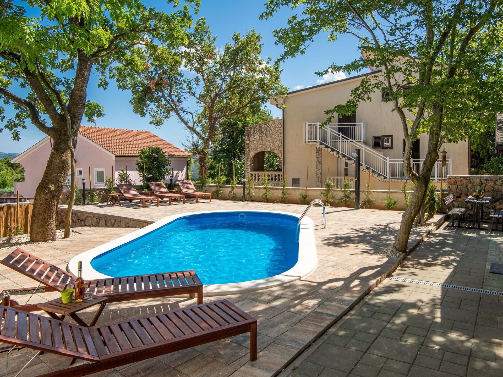 Ein Pool mit Liegestühlen, einer Steinmauer und einem Gebäude mit roten Ziegeldach.