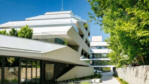 Ein modernes, mehrgeschossiges Gebäude mit einzigartigem architektonischen Design, das eine markante Treppe zu den oberen Stockwerken zeigt.