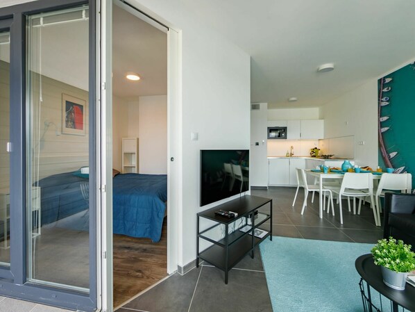 A modern apartment with a living area, a bedroom, and a kitchen.