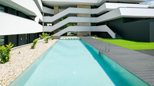 A modern building with a central pool, multiple balconies, and a flat roof. - Nice apartment for 4 people with pool, WIFI, A/C, TV, terrace and pets allowed (Balatonfüred)
