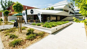A modern building with a restaurant named "MARINA" featuring outdoor seating and a garden area. - Nice apartment for 4 people with pool, WIFI, A/C, TV, terrace and pets allowed (Balatonfüred)