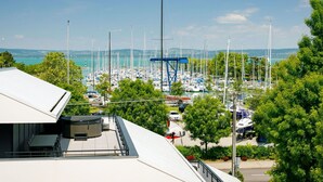 Un puerto deportivo con numerosos veleros amarrados, cielo despejado y vista a colinas distantes.
