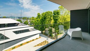 Un balcón moderno con vistas despejadas a un puerto deportivo y abundante vegetación.