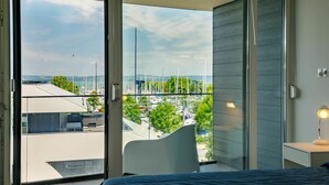 Un dormitorio con cama, mesita de noche y vista a un puerto deportivo a través de un ventanal.