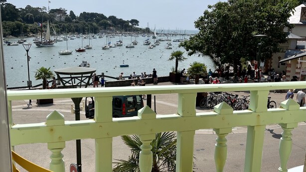 A balcony with yellow chairs and a table overlooking a marina with boats and a town in the background. - Seaview, Ocean view, villa on the historical harbor, city center (Pornic)