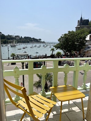 A balcony with yellow chairs and a table overlooking a marina with boats and a town in the background. - Seaview, Ocean view, villa on the historical harbor, city center (Pornic)