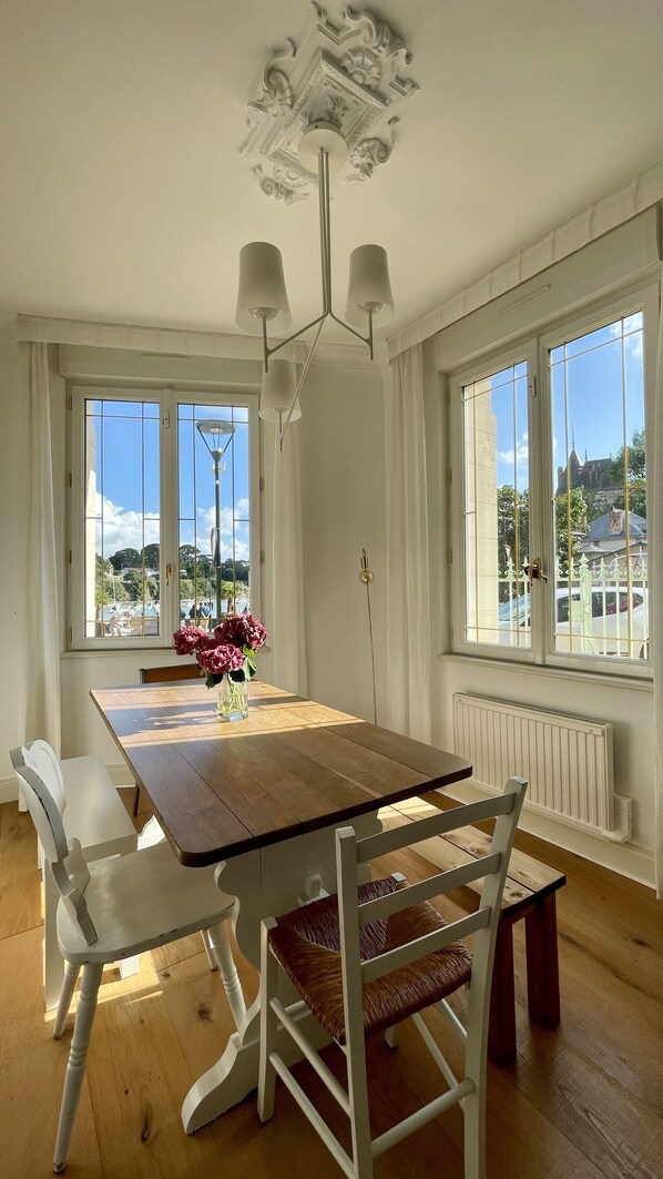 A dining room with a wooden table, white chairs, and a chandelier. - Seaview, Ocean view, villa on the historical harbor, city center (Pornic)