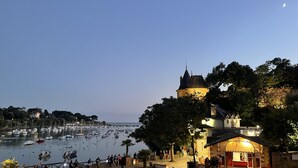 A historic building with a clock tower, a marina with boats, and a café with people sitting outside. - Seaview, Ocean view, villa on the historical harbor, city center (Pornic)