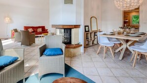 Un salon moderne doté d’une cheminée, d’un coin repas et d’un grand lustre.