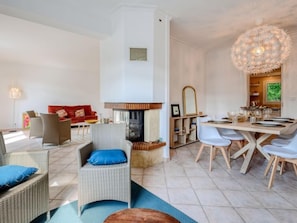 Una sala de estar moderna con chimenea, comedor y una gran lámpara de araña.