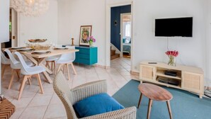 Un salon moderne comprenant un coin repas, un téléviseur fixé au mur et un escalier menant à une autre pièce.