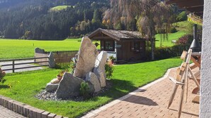 A rustic cabin with a stone waterfall feature, surrounded by a well-maintained lawn and a wooden fence. - Wildkogel by Interhome (Neukirchen am Großvenediger)