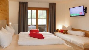 A hotel room with two beds, a television on the wall, and a view of the outdoors through the window. - Wildkogel by Interhome (Neukirchen am Großvenediger)