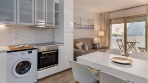 A modern kitchen with a washing machine, oven, and dining area with a table and chairs.
