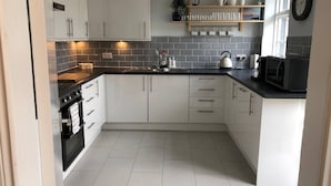 A modern kitchen with white cabinets, a black stove, and a tiled backsplash.