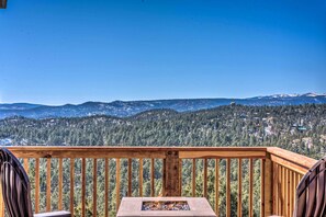 A wooden deck with a fire pit and chairs, overlooking a forested mountain range. - ‘Mountain’s Majesty’ Cabin w/ Hot Tub & Mtn Views! (Ruidoso)